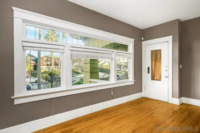 a view of an empty room with wooden floor and a fireplace
