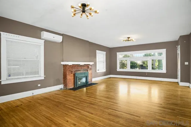 a view of an empty room with window and wooden floor