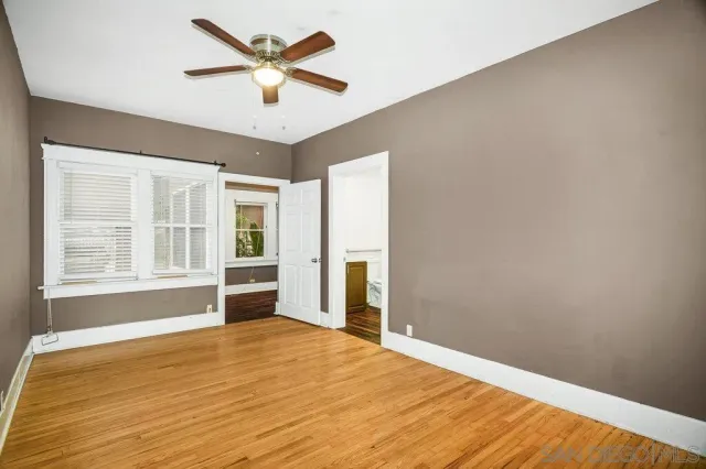 a view of an empty room with wooden floor and a window