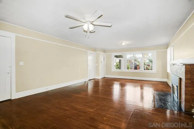 a view of an empty room with window and wooden floor