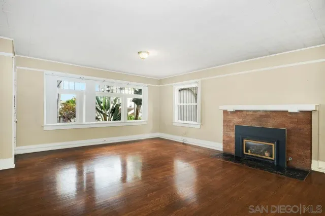 an empty room with floor to ceiling windows and fireplace