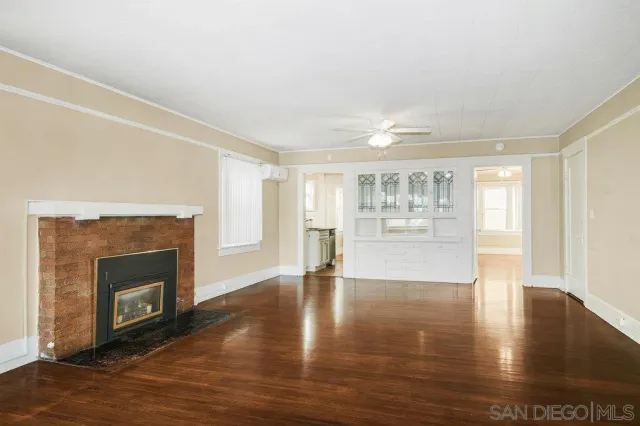 a view of an empty room with wooden floor and a fireplace