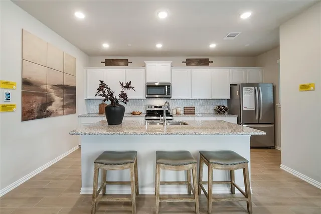 a kitchen with stainless steel appliances granite countertop a dining table chairs and refrigerator