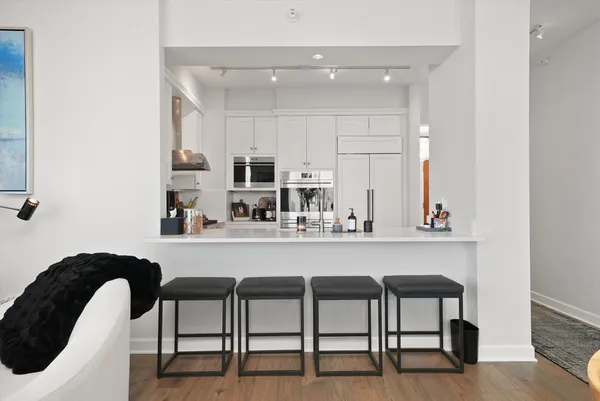 a kitchen with stainless steel appliances granite countertop a table chairs and a refrigerator