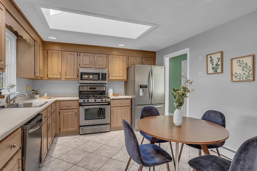 31 Hemlock Road Reading, MA 01867 - Photo 8 of 28 a kitchen with stainless steel appliances granite countertop a stove a sink dishwasher a dining table and chairs