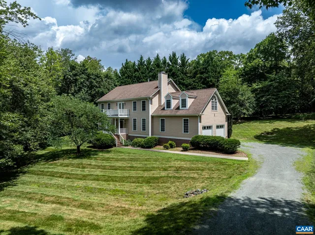 a view of a house with a big yard plants and large trees