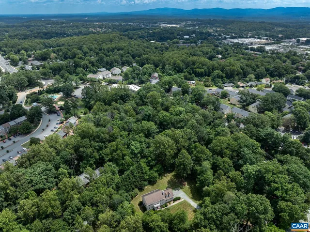an aerial view of residential houses with outdoor space and trees
