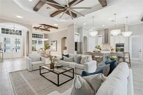 a living room with furniture kitchen view and a chandelier