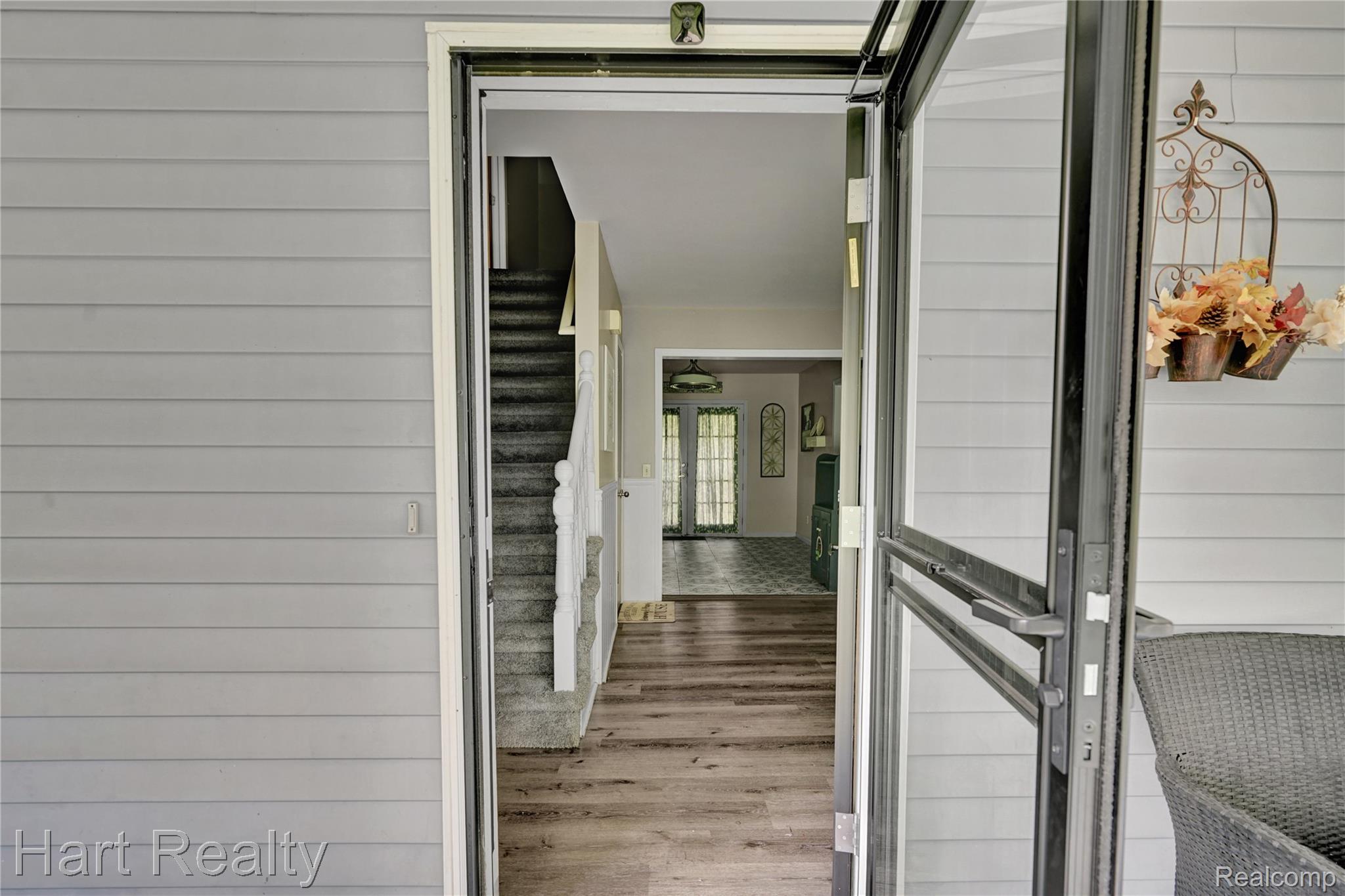 7167 Brown School Road North Branch, MI 48461 - Photo 5 of 51 Entryway featuring wood-finish flooring, a carpeted staircase with white balusters, and a screen door