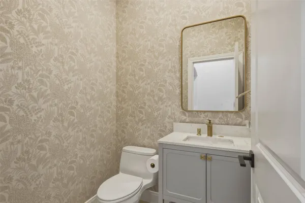a bathroom with a toilet sink vanity and mirror