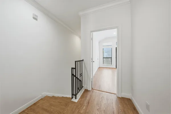 a view of a hallway with wooden floor and a bathroom