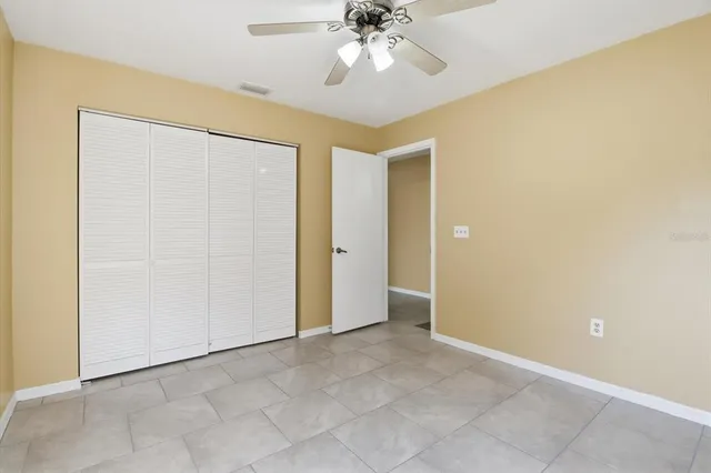a view of an empty room and chandelier fan