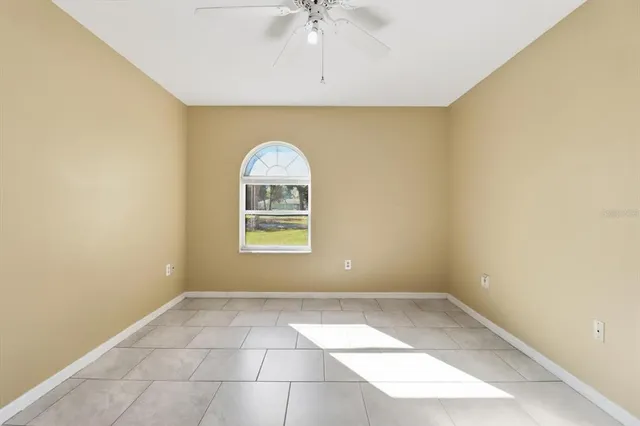an empty room with a window and a ceiling fan