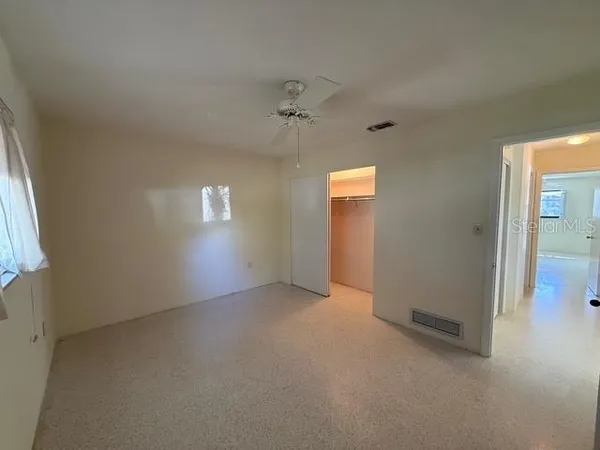 an empty room with windows and fan