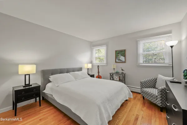 a bedroom with a bed wooden floor and a lamp on table