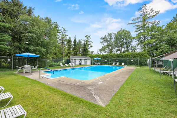 a view of a swimming pool with lawn chairs under an umbrella