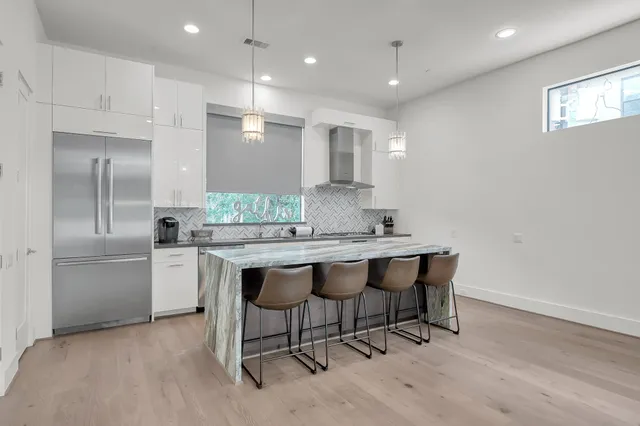 a kitchen with stainless steel appliances granite countertop a sink a stove a refrigerator and a refrigerator