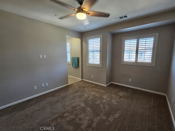 an empty room with windows and chandelier fan
