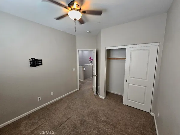an empty room with closet and a chandelier fan
