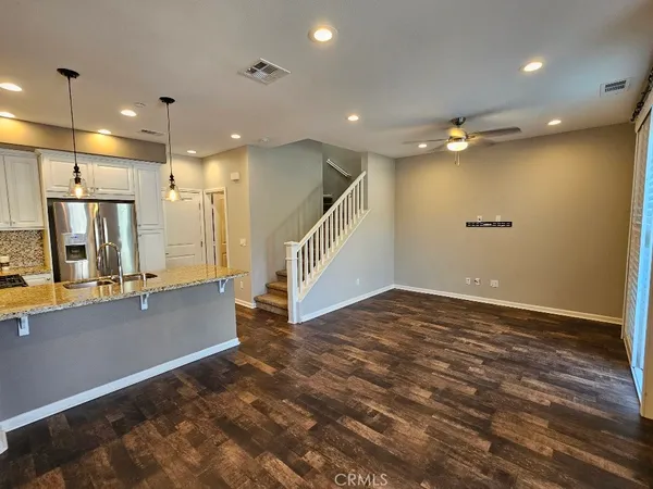 a view of an empty room with wooden floor and a bathroom