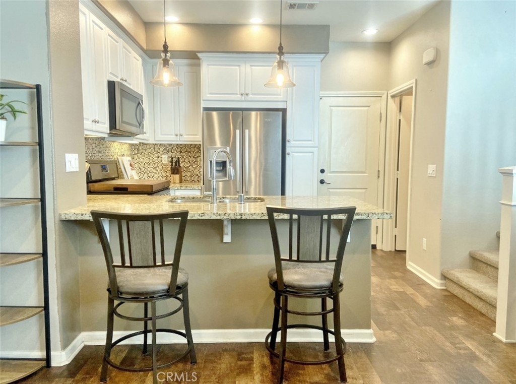 44011 Rivo Court Temecula, CA 92592 - Photo 10 of 34 a kitchen with stainless steel appliances granite countertop a dining table chairs and a refrigerator