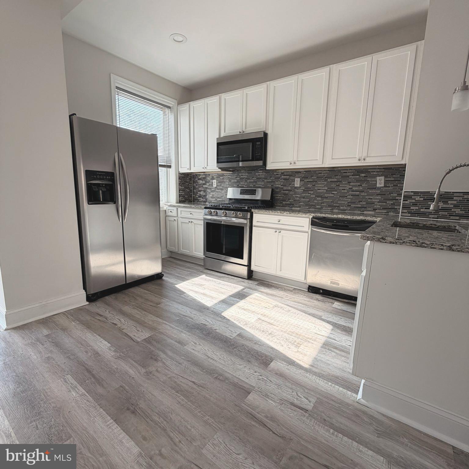 2631 West Cold Spring Lane Baltimore, MD 21215 - Photo 4 of 20 a kitchen with granite countertop a refrigerator stove and microwave