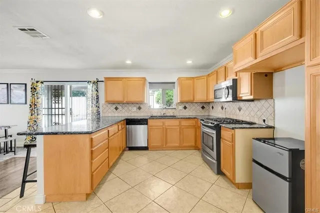 a large kitchen with stainless steel appliances granite countertop a stove a sink dishwasher and a refrigerator