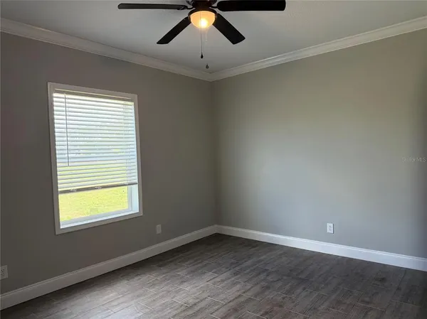 a view of an empty room with window and chandelier fan