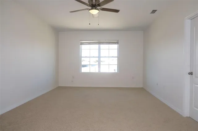 an empty room with a ceiling fan and carpet