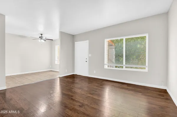 a view of an empty room with wooden floor and a window