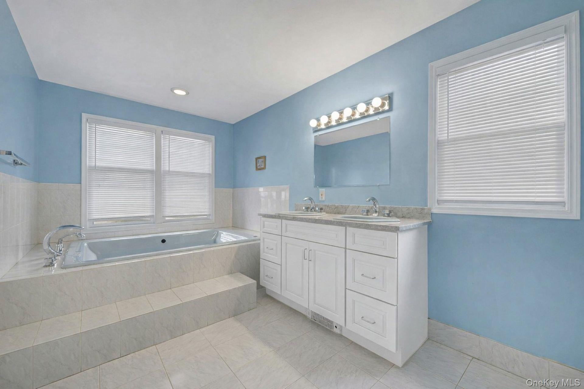 97 Bradley Road Scarsdale, NY 10583 - Photo 15 of 27 a bathroom with a granite countertop sink a large mirror and a bathtub