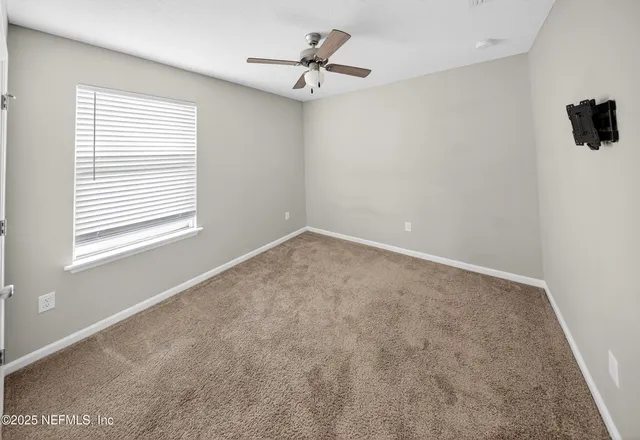 an empty room with a window and a fan