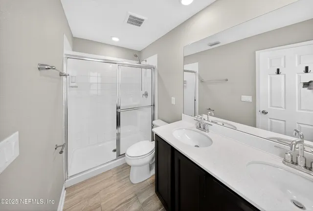 a bathroom with a double vanity sink toilet mirror and shower