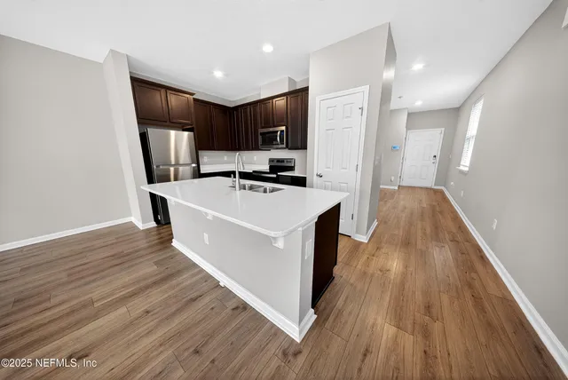 a view of a kitchen with wooden floor and electronic appliances