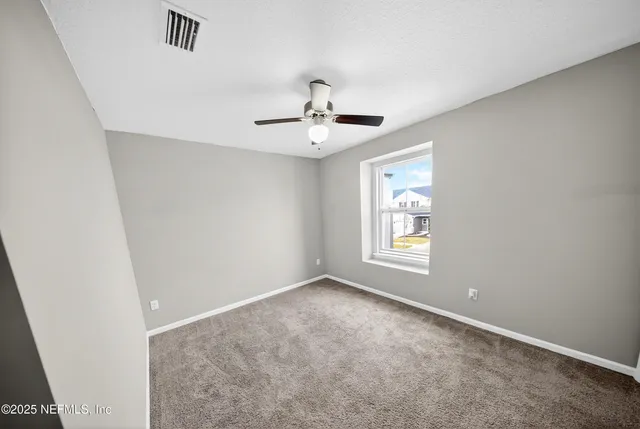 an empty room with windows and ceiling fan