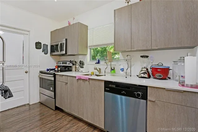 a kitchen with stainless steel appliances white cabinets sink and wooden floor