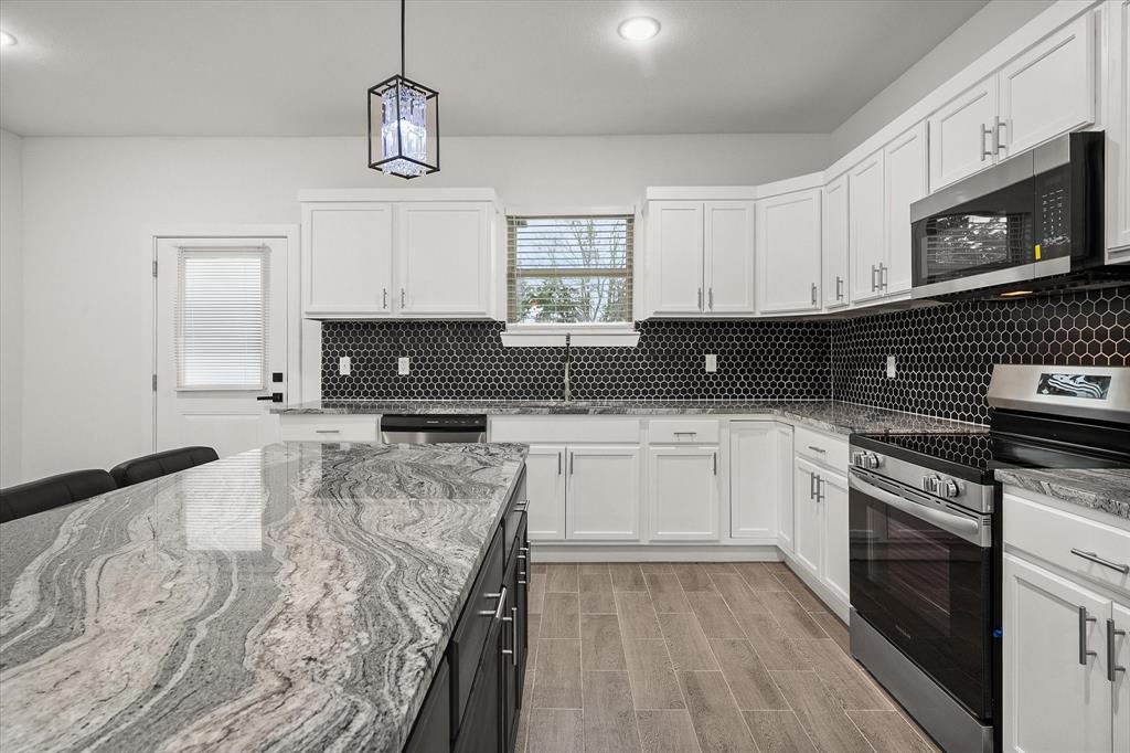 6771 Northwest County Road 1146 Barry, TX 75102 - Photo 17 of 34 a kitchen with stainless steel appliances granite countertop a stove a sink and a microwave