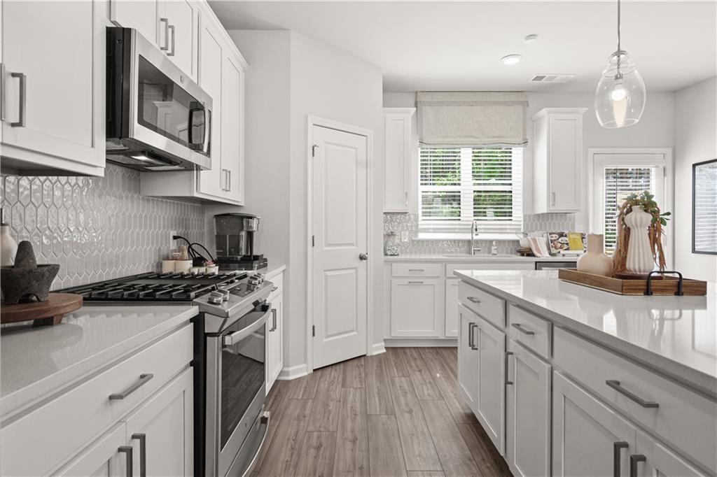 66 Wilder Ridge Way Lawrenceville, GA 30044 - Photo 12 of 44 a kitchen with stainless steel appliances granite countertop a stove a sink dishwasher and white cabinets with wooden floor