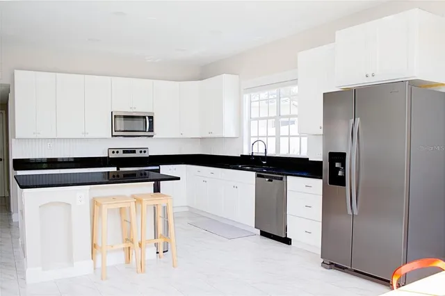 a kitchen with granite countertop white cabinets and stainless steel appliances