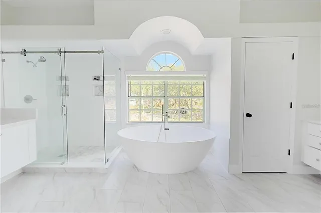 a bathroom with a white tub shower and window