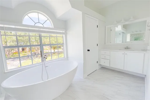a spacious bathroom with a tub and a large window