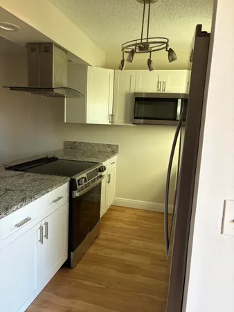 a kitchen with granite countertop a sink a stove top oven and cabinetry