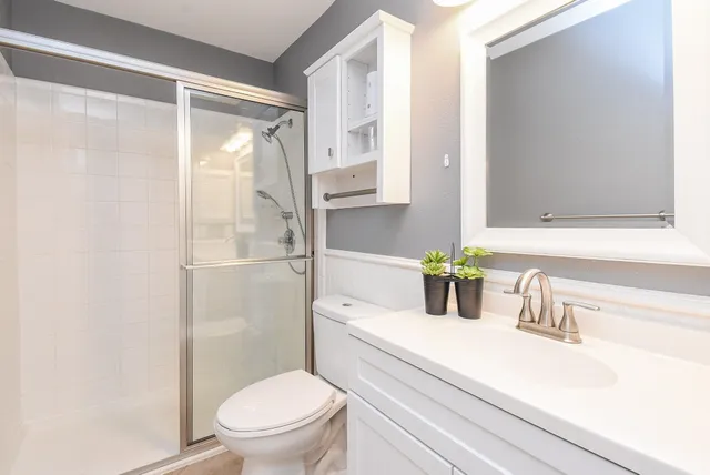 a bathroom with a granite countertop sink a toilet a mirror and shower