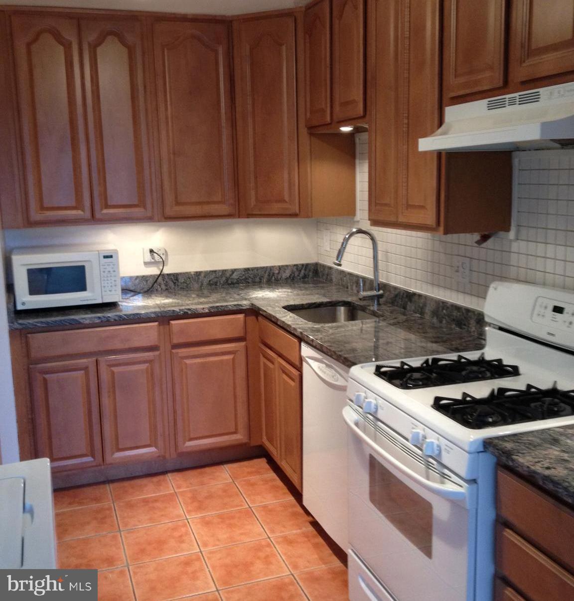 a kitchen with granite countertop stainless steel appliances a stove a microwave oven and a sink with cabinets