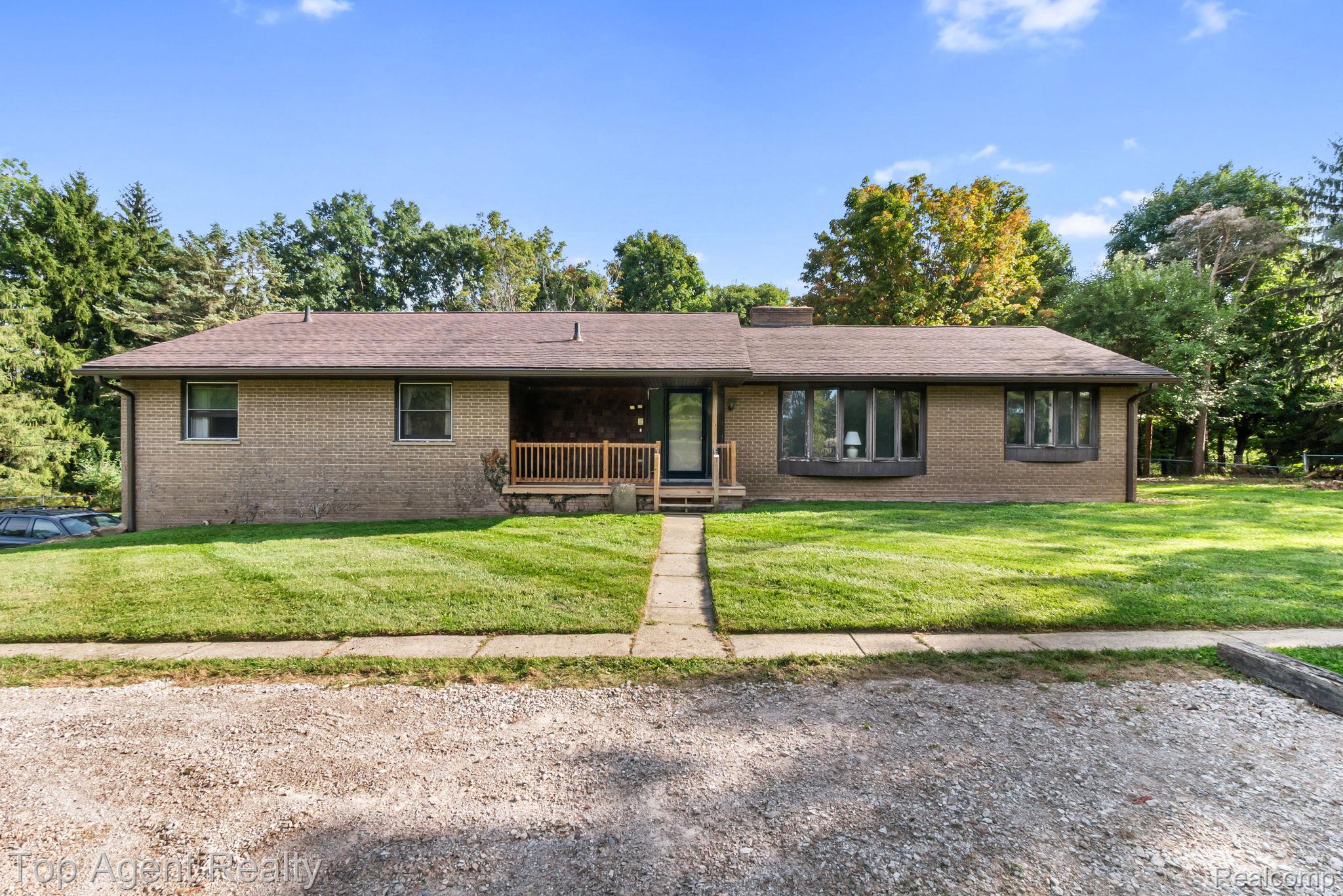8269 Currie Road Northville, MI 48168 - Photo 1 of 80 Brick exterior with a covered entry, wood railing, and bay windows