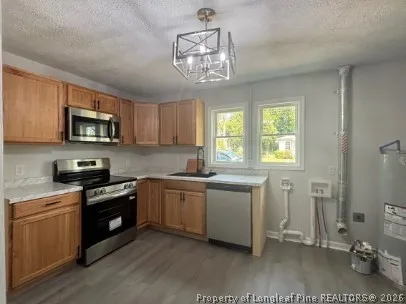 a kitchen with stainless steel appliances granite countertop a stove a sink dishwasher a refrigerator and a microwave oven with wooden floor