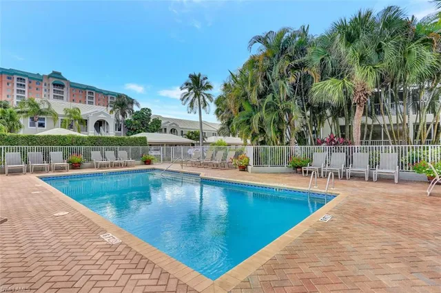 a view of a swimming pool with a lawn chairs under an umbrella