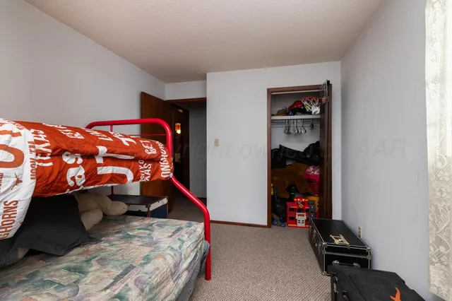 a bedroom with a bed and a flat tv screen on dresser