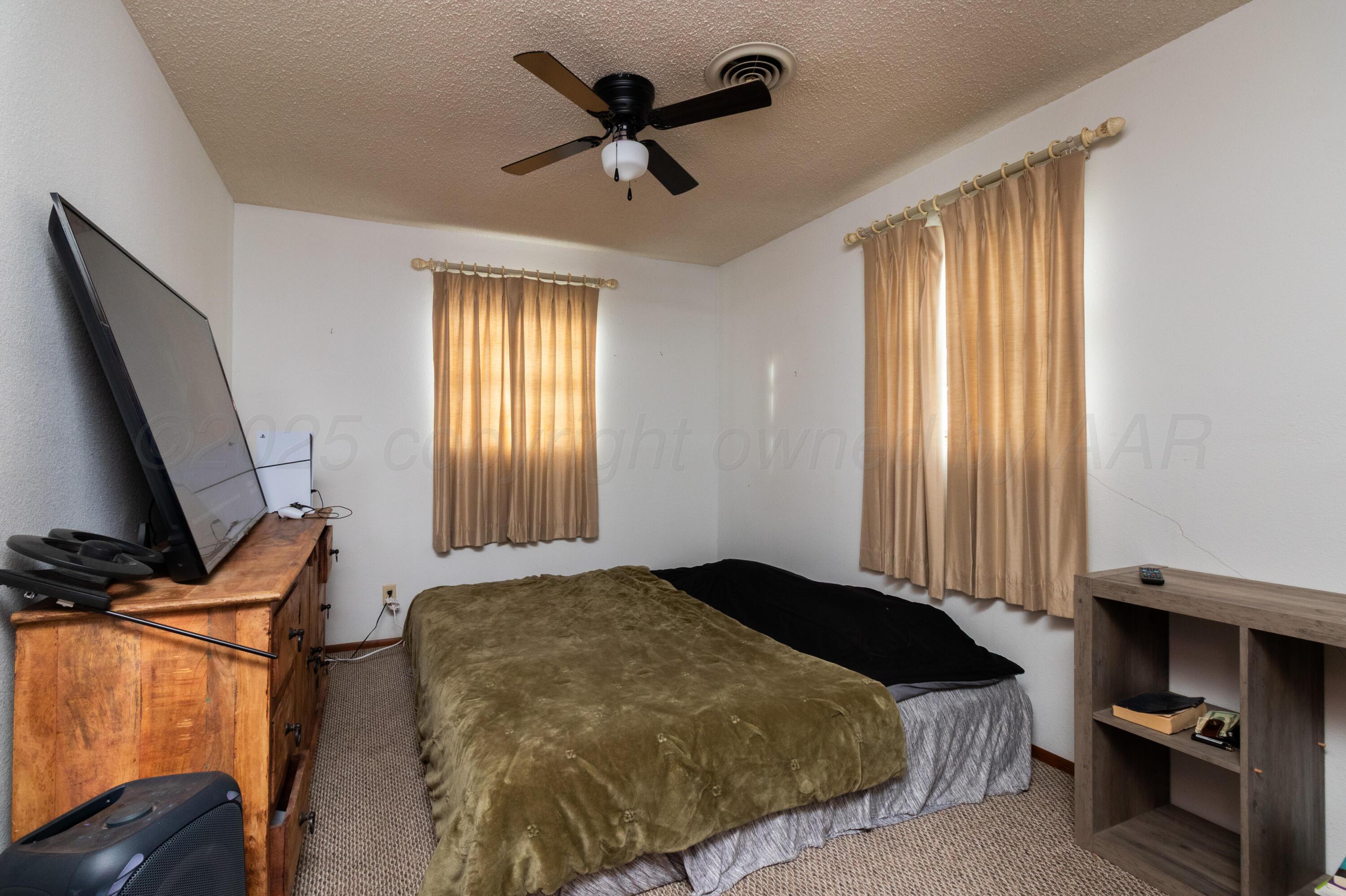 103 Jefferson Street Skellytown, TX 79080 - Photo 22 of 35 a bedroom with a bed and a flat tv screen on dresser
