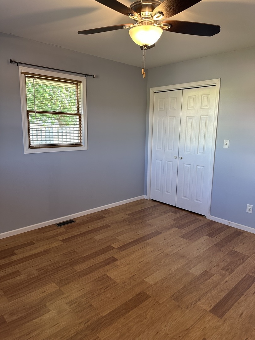 1691 Bilter Road Aurora, IL 60502 - Photo 9 of 19 an empty room with wooden floor chandelier fan and windows